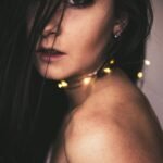 closeup photo of woman with string lights on neck