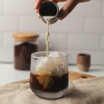 a hand pouring a drink into a glass